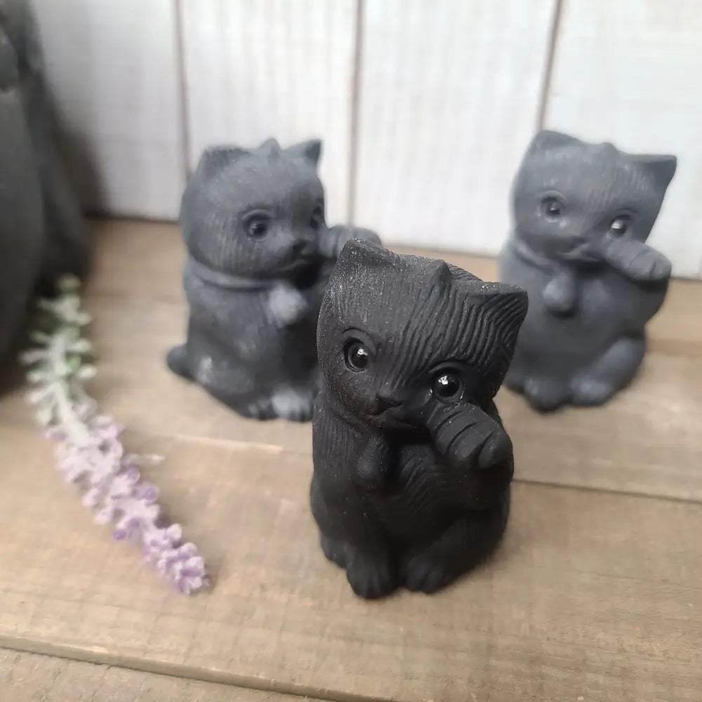 Hand-carved 2-inch Black Obsidian cuddly cat figurine with a glossy finish, featuring a sweet, snuggly pose, displayed on a white background.