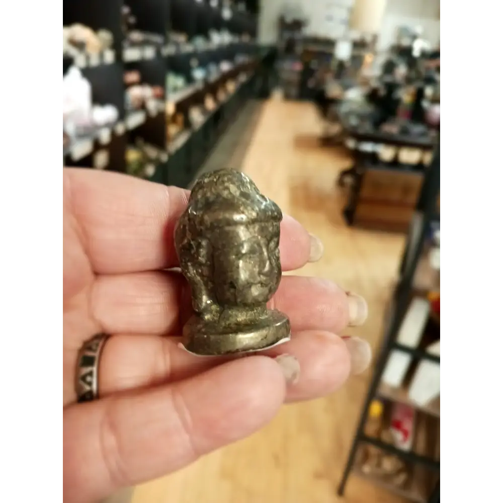 Hand-carved 1 1/2 inch tall Buddha head figurines in assorted crystal materials such as amethyst, rose quartz, clear quartz, and jade, displayed on a white background.