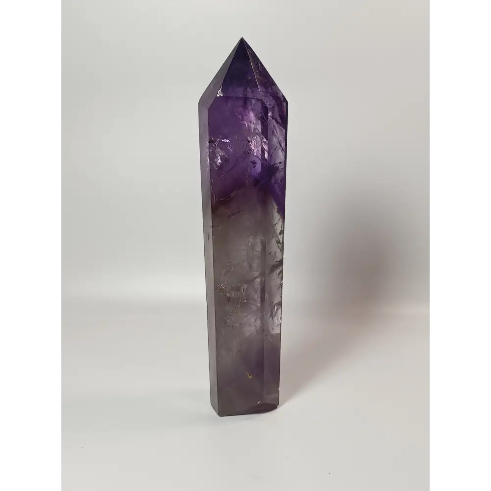 Polished freestanding Amethyst wand with deep purple hues and natural clarity, displayed on a white background.