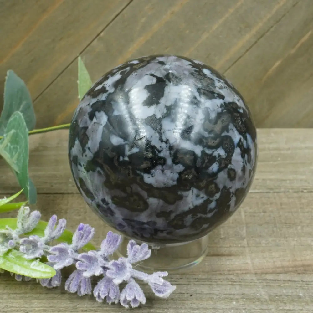 Hand-polished Indigo Gabbro sphere featuring swirling indigo, black, and gray patterns, displayed on a white background.