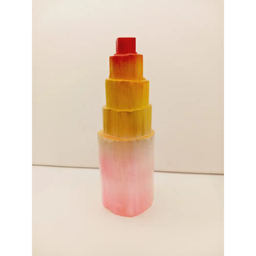 Rainbow selenite tiered tower, polished with a vibrant rainbow sheen and step-like design, displayed on a white background.