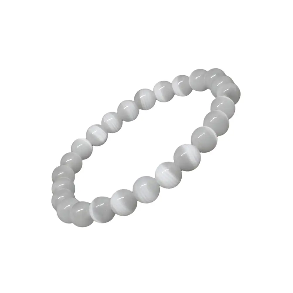 A white selenite bracelet with round beads laid out on a black surface.