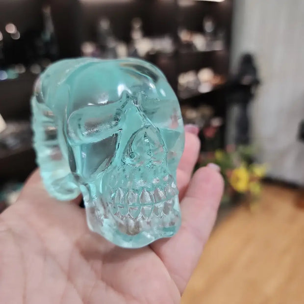 Aqua obsidian skull carving with prominent horns, featuring vibrant blue hues and intricate details, displayed on a white background. Perfect for transformation, protection, and bold mystical decor.


