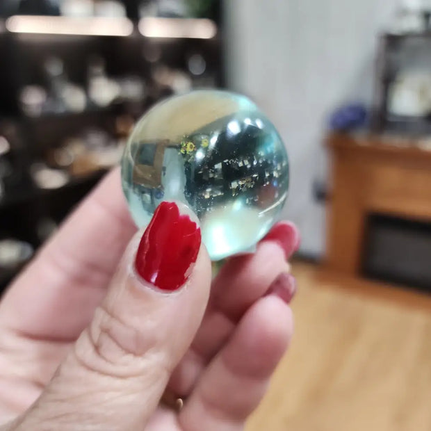 Polished aqua obsidian sphere with vibrant blue hues, displayed on a white background. Perfect for calming energy, protection, and spiritual clarity.