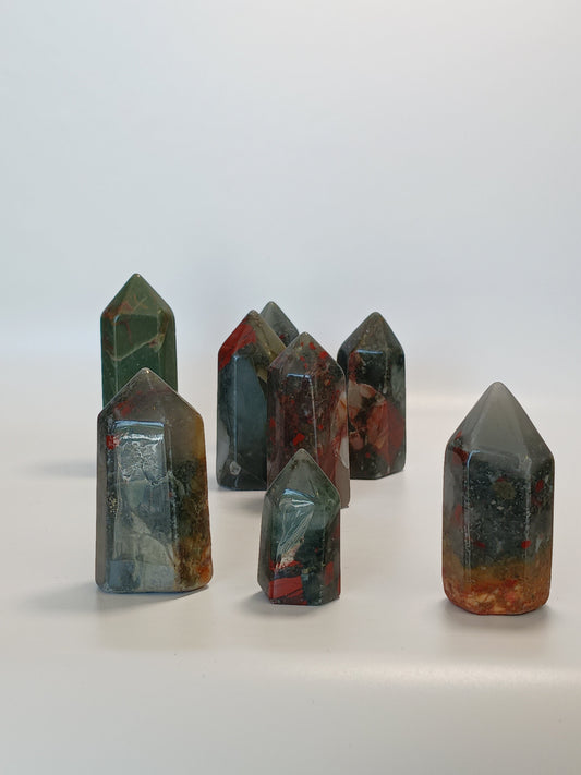 Hand-carved Bloodstone point, 2 to 2.5 inches tall, featuring deep green with natural red flecks, displayed on a white background.

