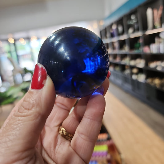 Polished blue obsidian sphere with vibrant blue hues, displayed on a white background. Perfect for clarity, communication, and calming energy.