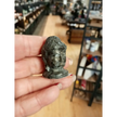 Hand-carved 1 1/2 inch tall Buddha head figurines in assorted crystal materials such as amethyst, rose quartz, clear quartz, and jade, displayed on a white background.