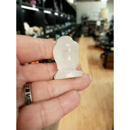 Hand-carved 1 1/2 inch tall Buddha head figurines in assorted crystal materials such as amethyst, rose quartz, clear quartz, and jade, displayed on a white background.