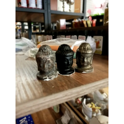 Hand-carved 1 1/2 inch tall Buddha head figurines in assorted crystal materials such as amethyst, rose quartz, clear quartz, and jade, displayed on a white background.