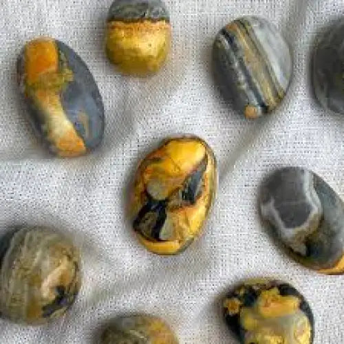 Polished bumble bee jasper tumble with bright yellow, orange, and black bands, displayed on a white background. Perfect for confidence, creativity, and vibrant energy.