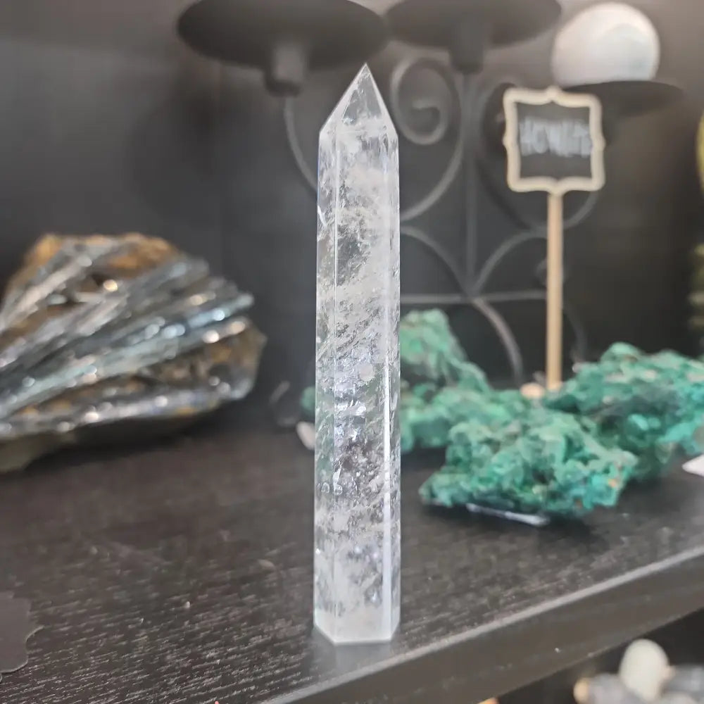 Hand-carved Clear Quartz tower featuring brilliant transparency and natural inclusions, displayed on a white background.