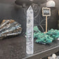 Hand-carved Clear Quartz tower featuring brilliant transparency and natural inclusions, displayed on a white background.