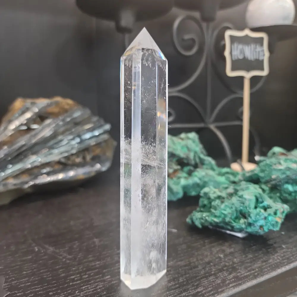 Hand-carved Clear Quartz tower featuring brilliant transparency and natural inclusions, displayed on a white background.