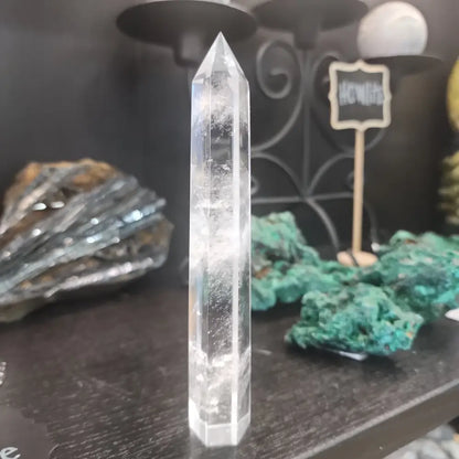 Hand-carved Clear Quartz tower featuring brilliant transparency and natural inclusions, displayed on a white background.