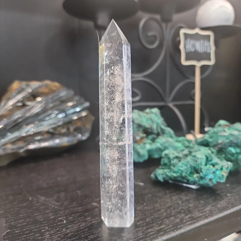 Hand-carved Clear Quartz tower featuring brilliant transparency and natural inclusions, displayed on a white background.