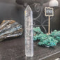 Hand-carved Clear Quartz tower featuring brilliant transparency and natural inclusions, displayed on a white background.