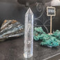 Hand-carved Clear Quartz tower featuring brilliant transparency and natural inclusions, displayed on a white background.