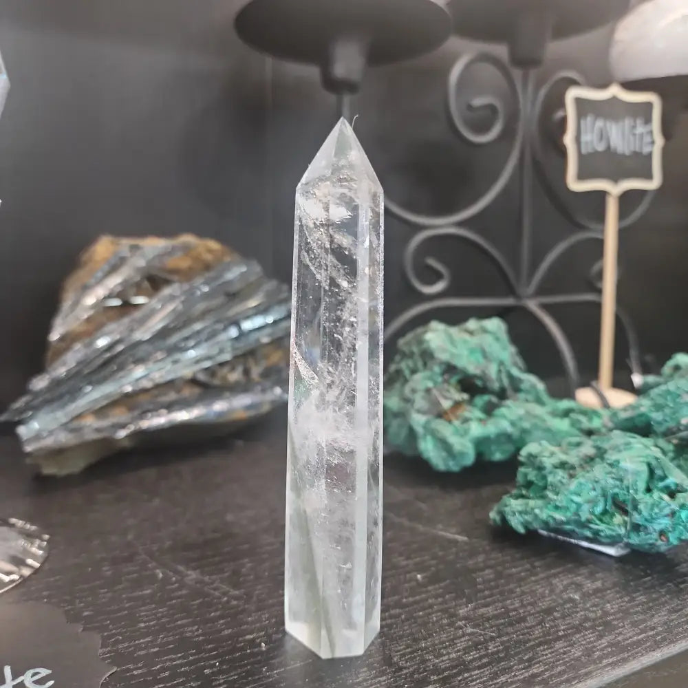 Hand-carved Clear Quartz tower featuring brilliant transparency and natural inclusions, displayed on a white background.