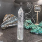 Hand-carved Clear Quartz tower featuring brilliant transparency and natural inclusions, displayed on a white background.