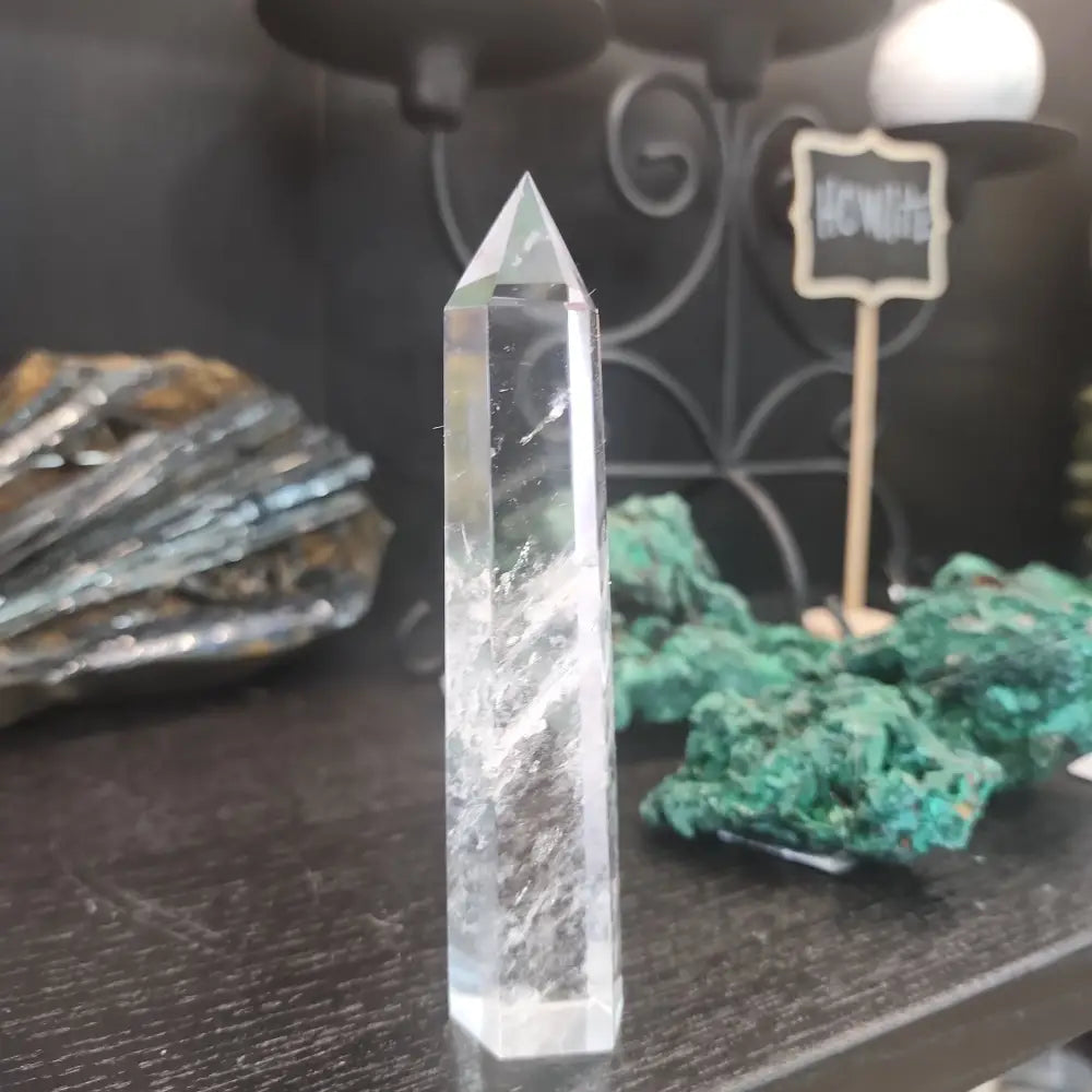 Hand-carved Clear Quartz tower featuring brilliant transparency and natural inclusions, displayed on a white background.