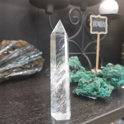 Hand-carved Clear Quartz tower featuring brilliant transparency and natural inclusions, displayed on a white background.