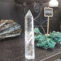 Hand-carved Clear Quartz tower featuring brilliant transparency and natural inclusions, displayed on a white background.