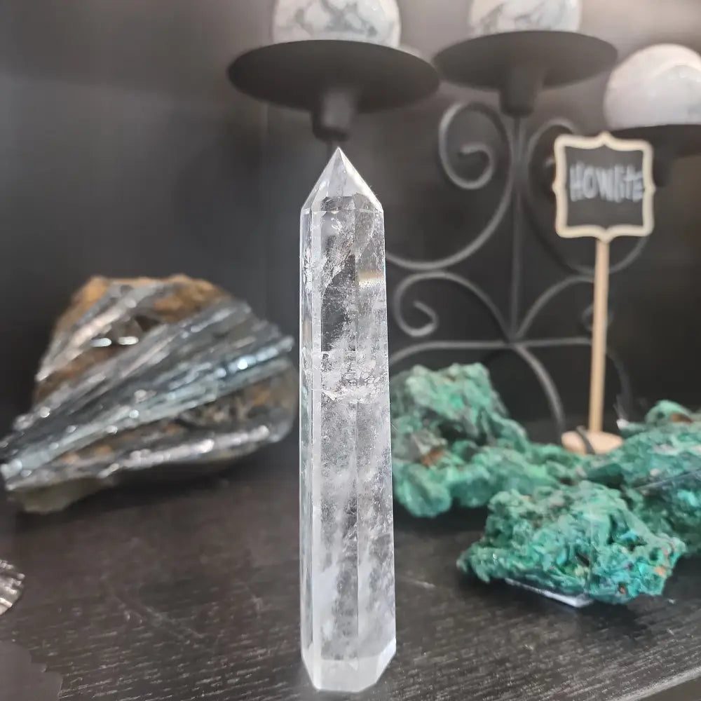Hand-carved Clear Quartz tower featuring brilliant transparency and natural inclusions, displayed on a white background.