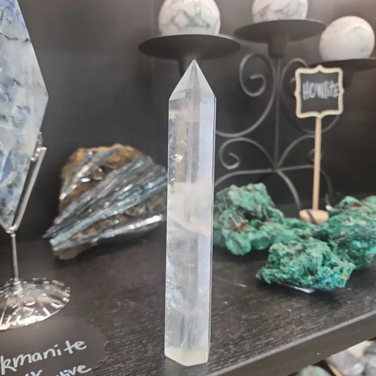 Hand-carved Clear Quartz tower featuring brilliant transparency and natural inclusions, displayed on a white background.