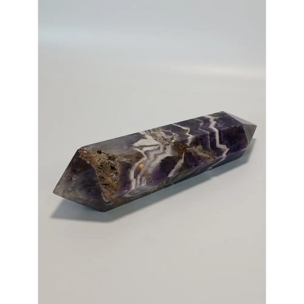 Double terminated Dream Amethyst crystal featuring bold purple and white chevron patterns, displayed on a white background.