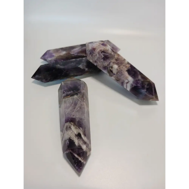 Double terminated Dream Amethyst crystal featuring bold purple and white chevron patterns, displayed on a white background.