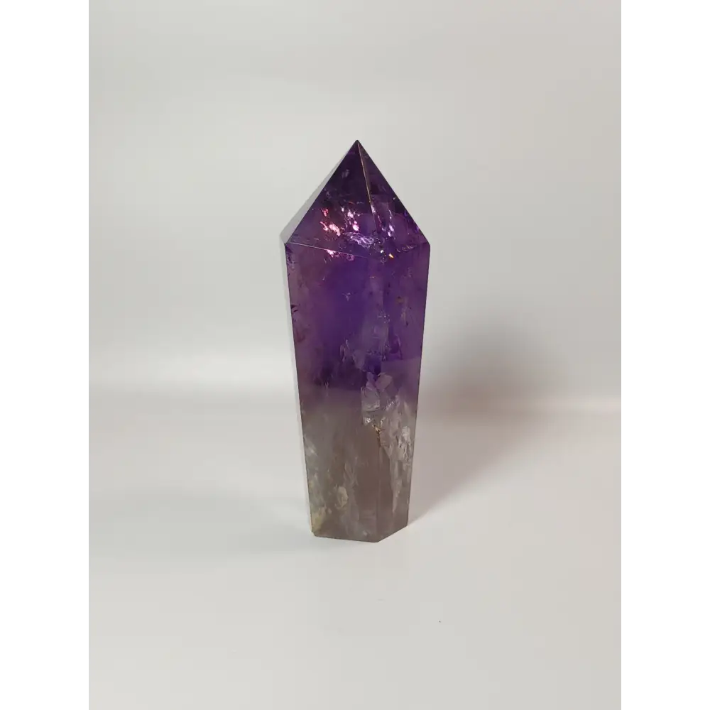 Polished freestanding Amethyst wand with deep purple hues and natural clarity, displayed on a white background.