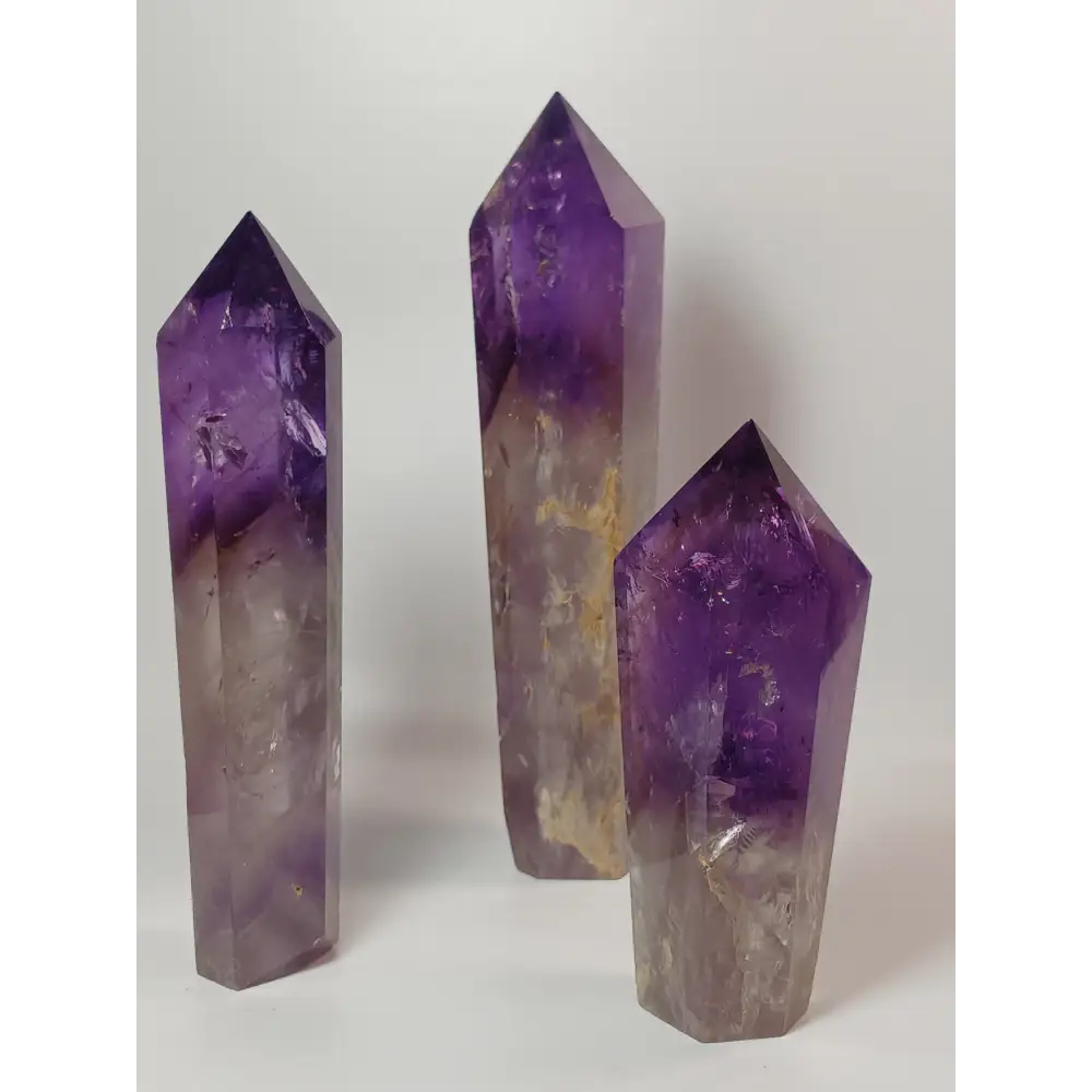 Polished freestanding Amethyst wand with deep purple hues and natural clarity, displayed on a white background.