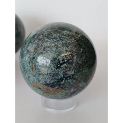 Hand-polished Green Mica sphere featuring sparkling, leafy-green hues and a glossy finish, displayed on a white background.