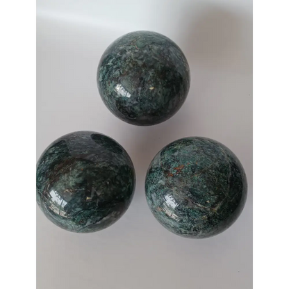 Hand-polished Green Mica sphere featuring sparkling, leafy-green hues and a glossy finish, displayed on a white background.
