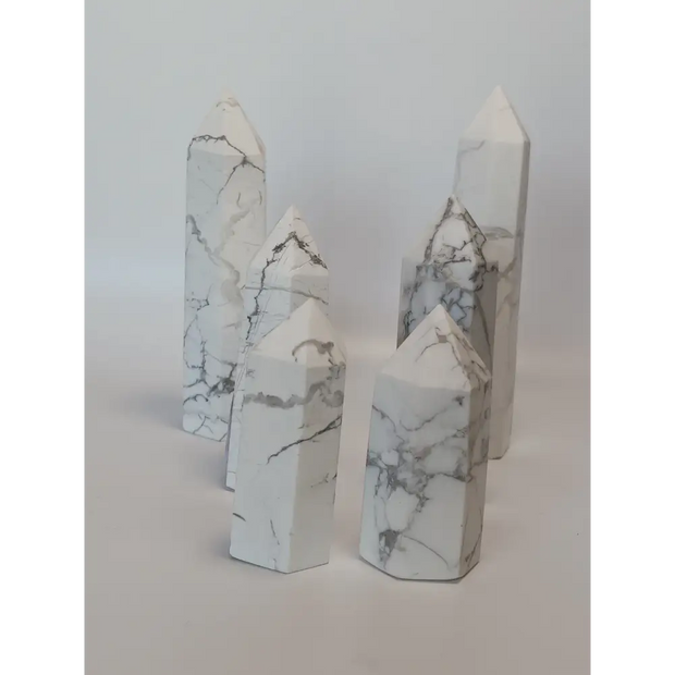 Hand-carved Howlite point featuring soft white coloring with graceful gray veining, displayed on a white background.