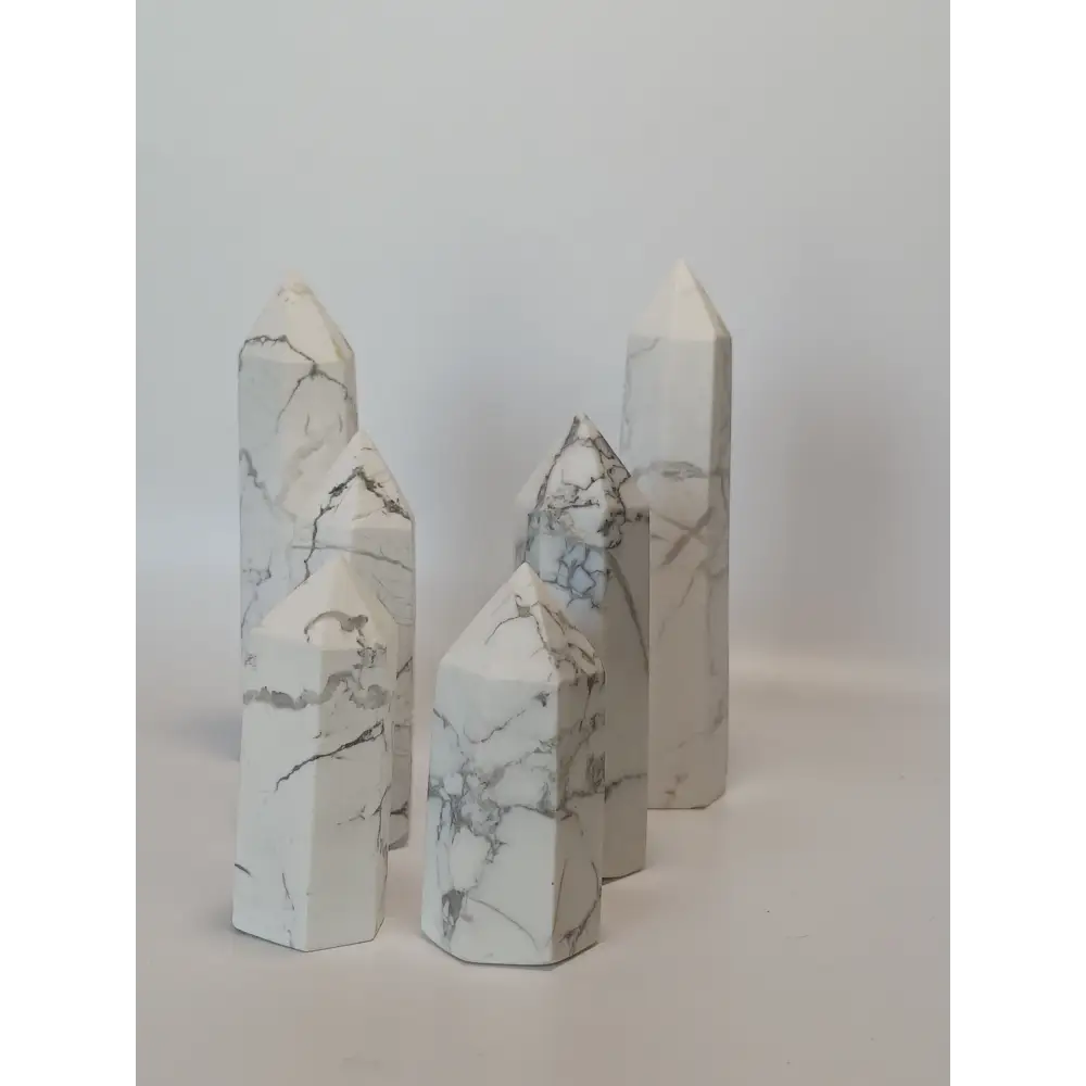 Hand-carved Howlite point featuring soft white coloring with graceful gray veining, displayed on a white background.