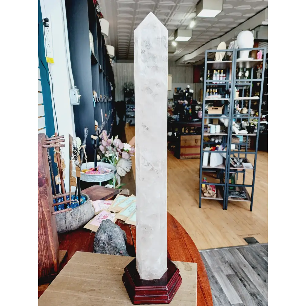 Huge clear quartz tower, polished and mounted on a sturdy stand, with brilliant clarity and natural inclusions, displayed on a white background.