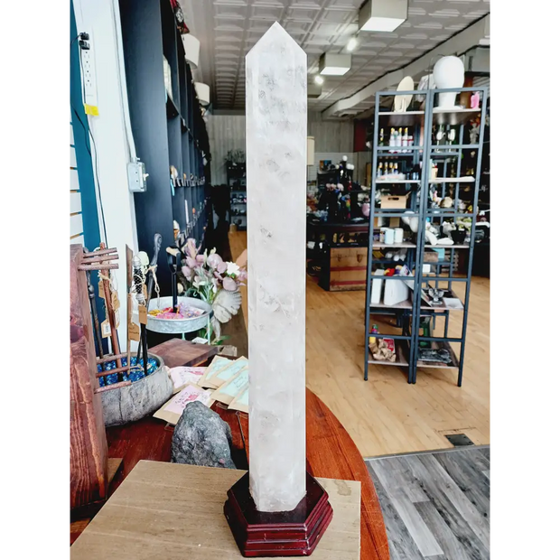 Huge clear quartz tower, polished and mounted on a sturdy stand, with brilliant clarity and natural inclusions, displayed on a white background.