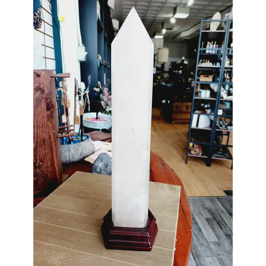 Huge clear quartz tower, polished and mounted on a sturdy stand, with brilliant clarity and natural inclusions, displayed on a white background.