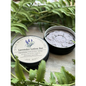 Lavender Lotion Bar in a round shape, surrounded by sprigs of fresh lavender and natural butters, displayed on a white background. Perfect for nourishing, soothing, and hydrating skin.