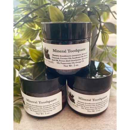 Mineral Toothpaste powder in a small jar, with a bamboo toothbrush beside it, displayed on a white background. Perfect for gently polishing and whitening teeth with natural minerals.