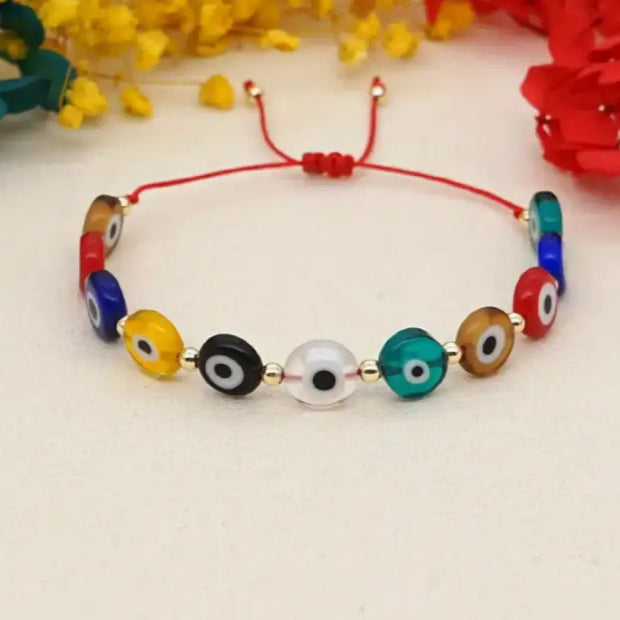 Colorful beaded bracelet with red string on a light background