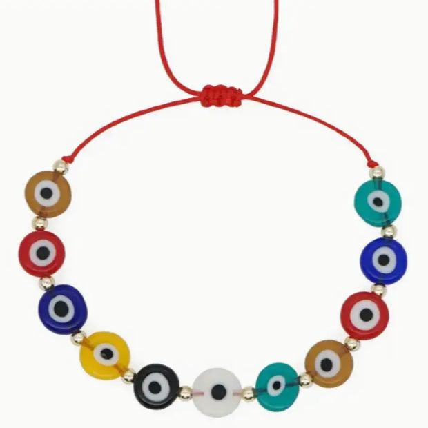 Necklace with colorful evil eye beads on a red cord against a white background
