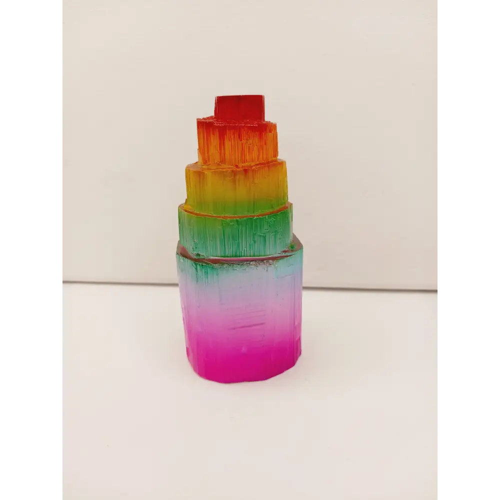 Rainbow selenite tiered tower, polished with a vibrant rainbow sheen and step-like design, displayed on a white background.