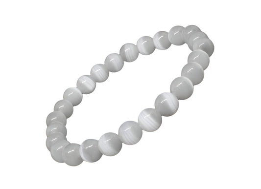 A white selenite bracelet with round beads laid out on a black surface.