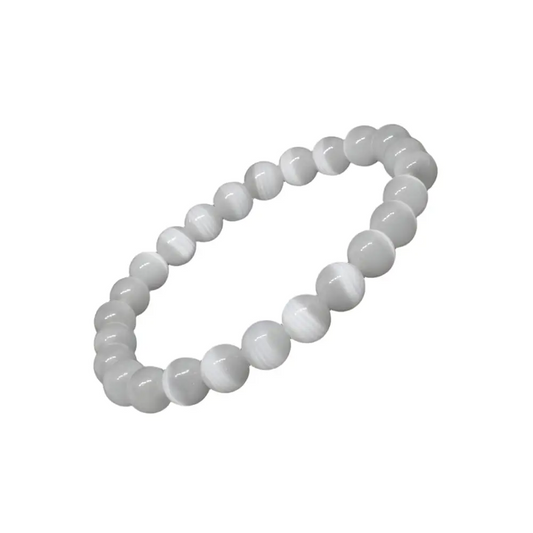 A white selenite bracelet with round beads laid out on a black surface.
