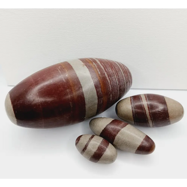 Shiva Lingam stones, polished with natural earthy patterns, available in sizes 1" to 8", displayed on a white background.