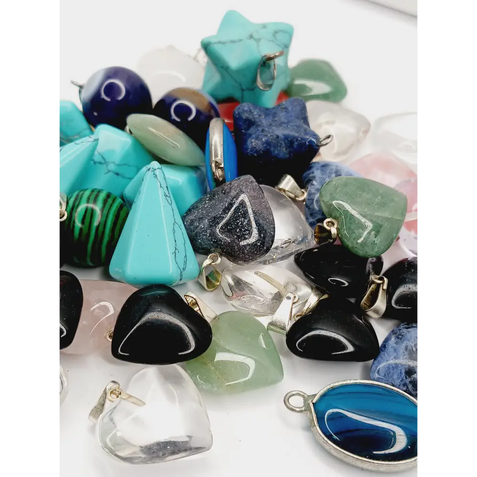 Assorted small stone pendants, each with polished gemstones in various colors and shapes, displayed on a white background.