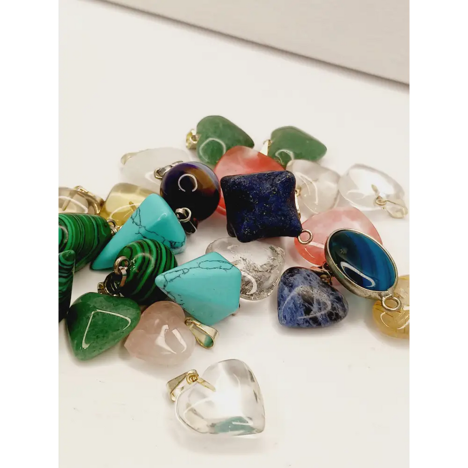 Assorted small stone pendants, each with polished gemstones in various colors and shapes, displayed on a white background.