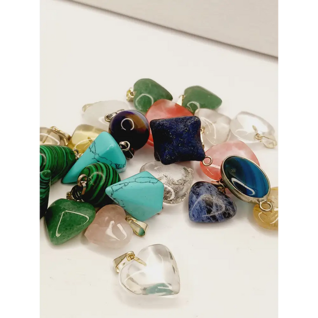 Assorted small stone pendants, each with polished gemstones in various colors and shapes, displayed on a white background.
